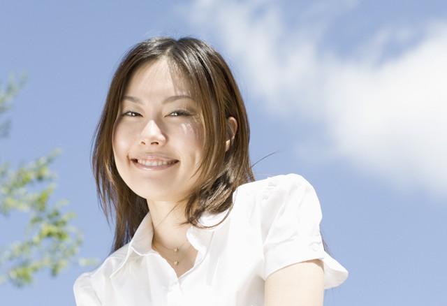 青空の下で笑いかける女性